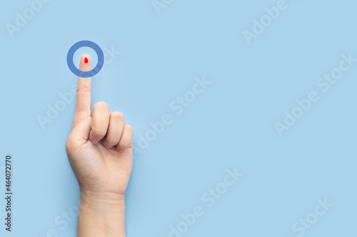 World diabetes day awareness concept. Finger with blood drop and blue circle of universal symbol for diabetes. Support for the fight against diabetes. photo