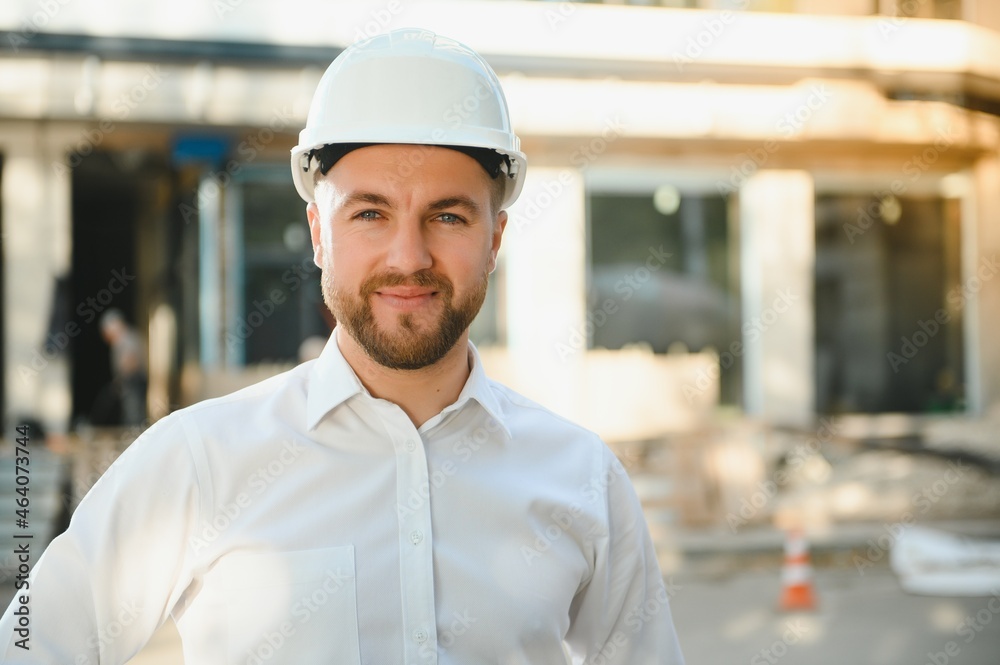 Successful engineer or architect, crane and building construction at backgrpound. Joyous businessman wearing helmet Successful engineer or architect, crane and building construction at backgrpound. Joyous businessman wearing helmet