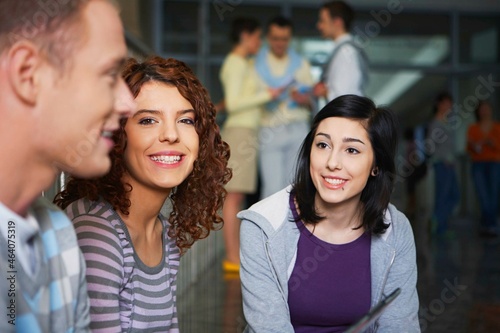 Close-up of smiling university students talking in hallway