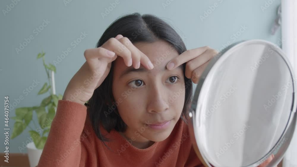 Asian young woman Squeezing acne skin looking on mirror Close-up face Asian young woman Squeezing acne skin looking on mirror Close-up face