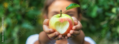 Fotografiet The child eats an apple in the garden. Selective focus.