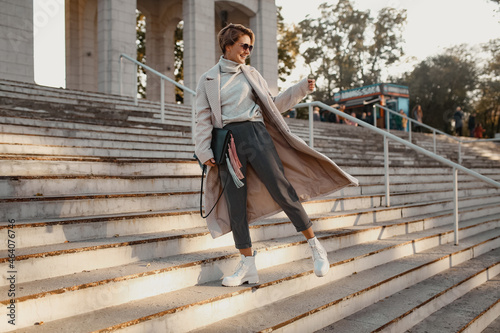 stylish fashionable woman walking in street in elegant style coat