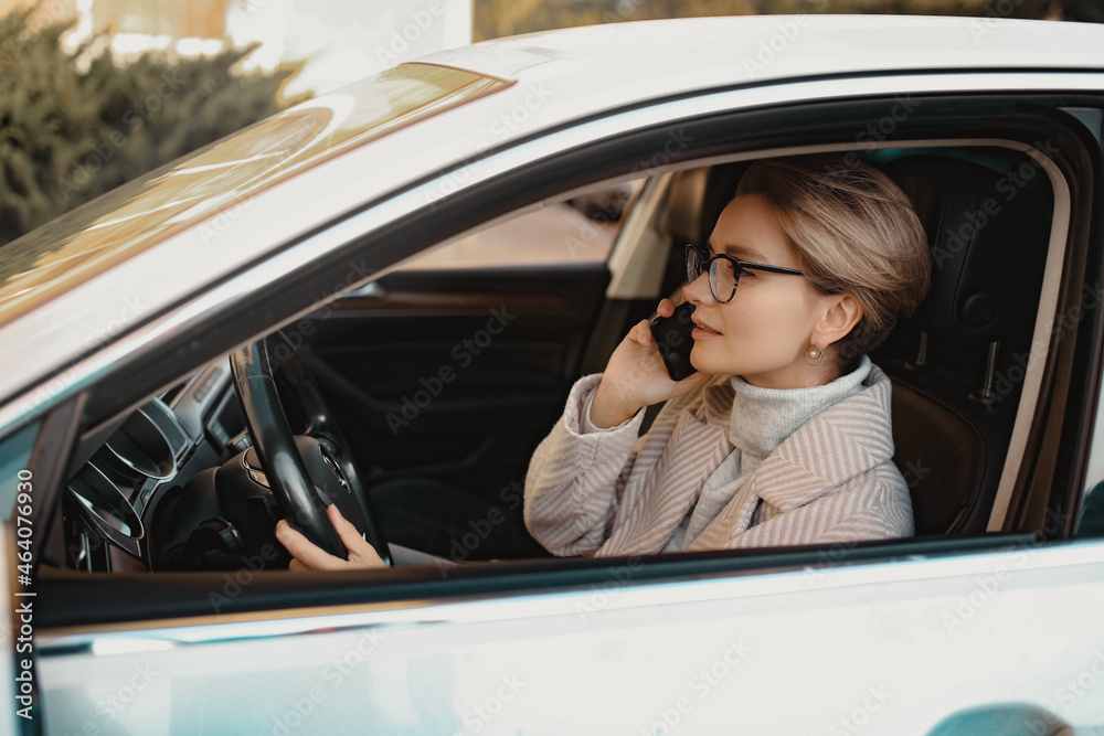 attractive stylish woman sitting in car dressed in coat
