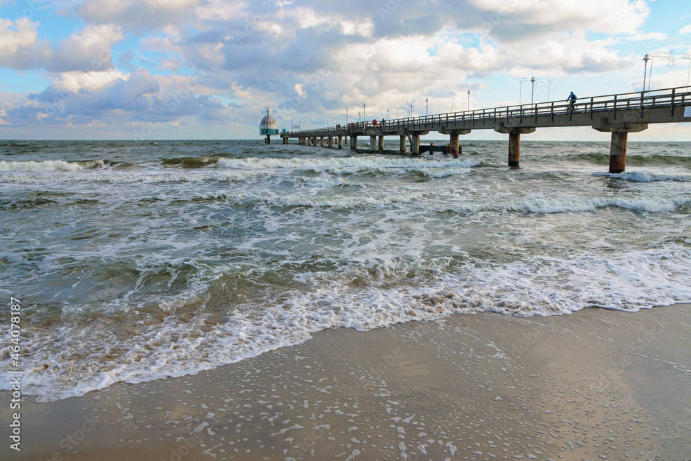 Zinnowitz seabridge with diving bell in the tourist resort at the Baltic Sea in Germany, windy weather with waves and blue sky with clouds, copy space