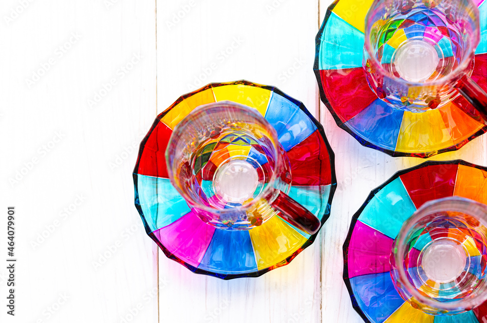 Fototapeta premium Multi-colored glass cups and saucers for coffee and tea stand on a wooden tray