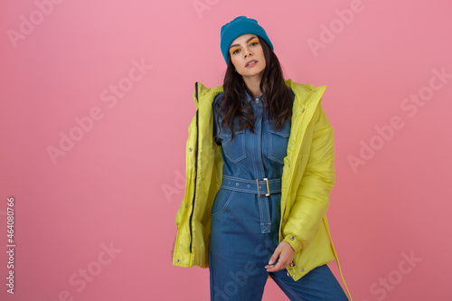 attractive active woman model posing on pink background in colorful winter down jacket of bright ryellow color, warm coat fashion trend photo