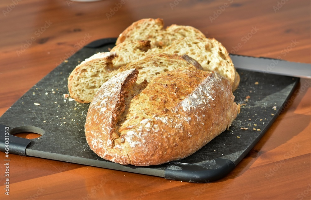 bread on a black board and a knife on a wooden table
