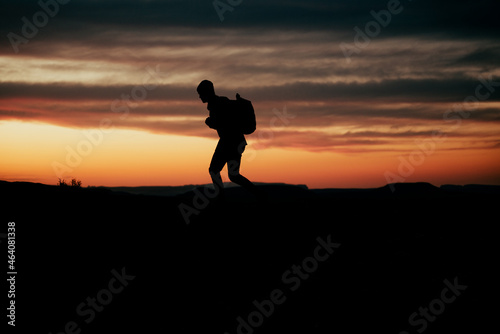 Caucasian male adventurer hiking in mountain during sunset wearing backpack