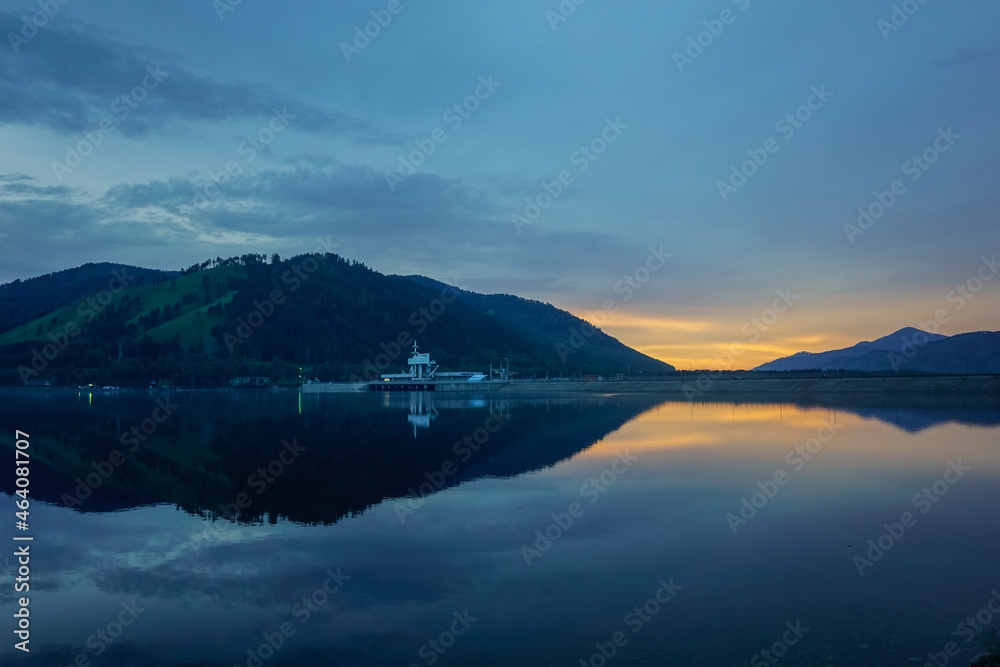 Beautiful Sayan mountains in the reflection of the Yenisei river at sunset