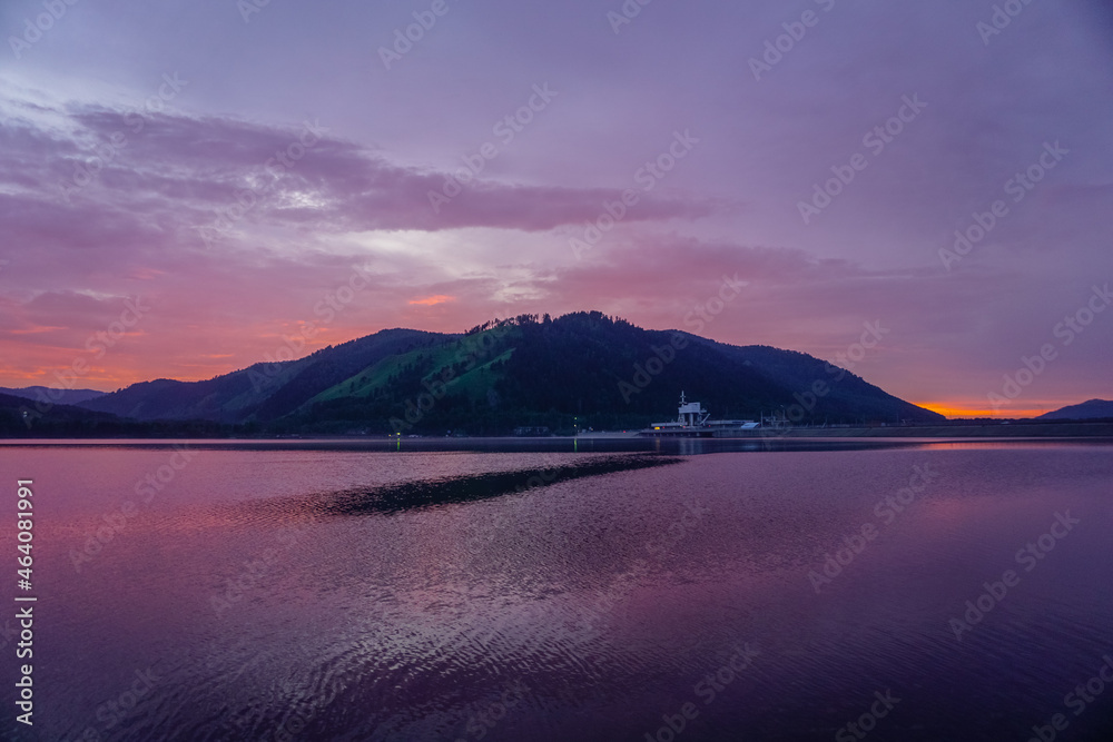 Beautiful Sayan mountains in the reflection of the Yenisei river at sunset