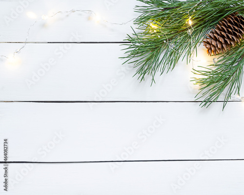 Christmas pine branch on white wooden background with cones and garland