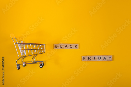Sale and Black Friday concept. Mini shopping cart on yellow background.