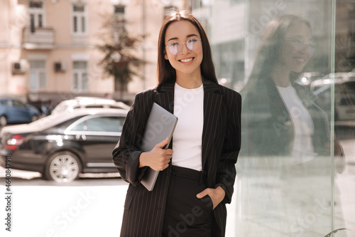 Fotografie Brunette business young asian woman with laptop in her hands not in full growth smiling at camera