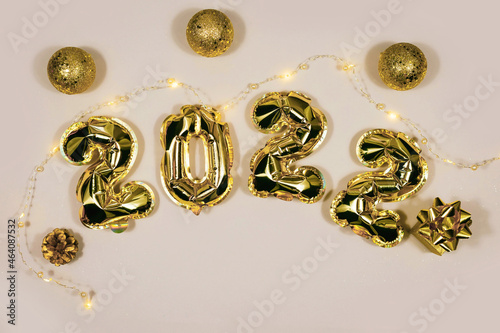 Golden 2022 balloons, gift, balls isolated on grey background. Helium balloons, gold foil numbers. Numbers for Happy New Year 2022. Party decoration, celebration, carnival.