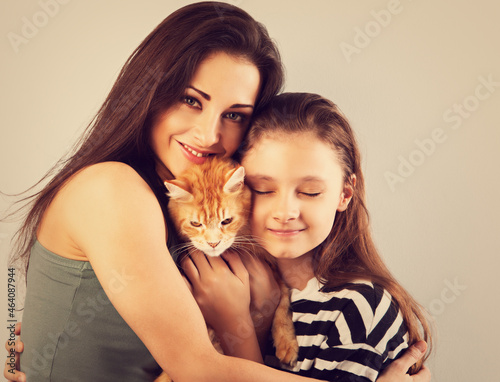 Happy young mother hugging her red maine coon kitten and daughter. Closeup portrait © nastia1983