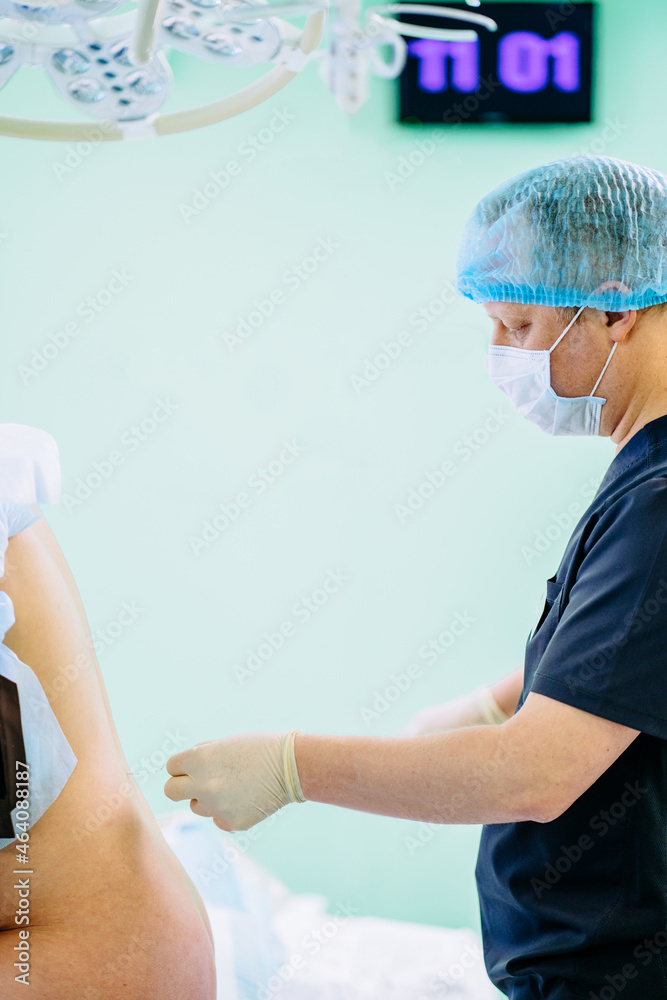 Vertical side view of male doctor injecting Epidural Anesthesia for pregnancy Labor during