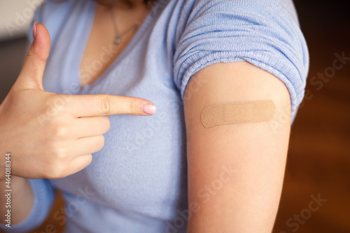 Young girl student showing adhesive bandage on her arm in the place of vaccination. Concept of vaccination