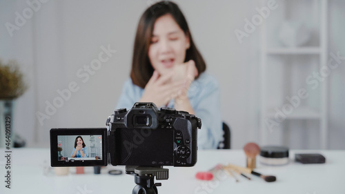 Happy smiling asian woman or beauty blogger with brush and camera recording video and waving hand at home. Beauty videoblog blogging people concept.