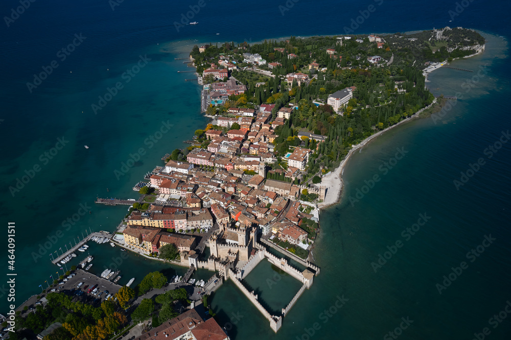Aerial view to the town of Sirmione, popular travel destination on Lake Garda in Italy.  Autumn in Italy on Lake Garda, Sirmione peninsula. Trees in the autumn season.