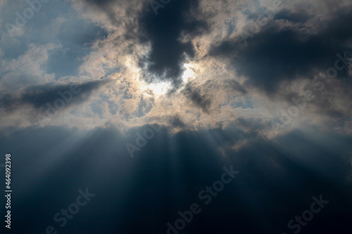 Ray of sun or sunbeam shining through the cloudy cumulus clouds floating in the skies, White grey fluffy clouds on sky before raining, Nature pattern background. © Sarawut