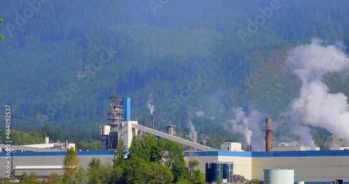 Establishing shot of Power plants generating smokes on the forest background in slow motion at summer day in Vancouver, Canada, North America. Day time on September 2021. Still camera. ProRes 422 HQ. photo