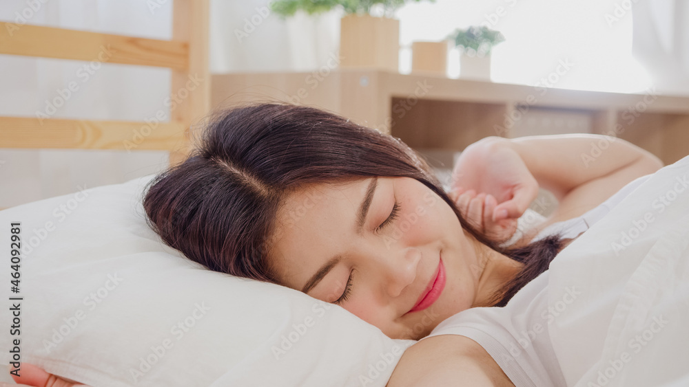 Beautiful attractive young Asian woman wake up, smiling and stretching her arms in her bed in bedroom. Young asia female use relax time at home. Lifestyle women relax at home concept. Beautiful attractive young Asian woman wake up, smiling and stretching her arms in her bed in bedroom. Young asia female use relax time at home. Lifestyle women relax at home concept.