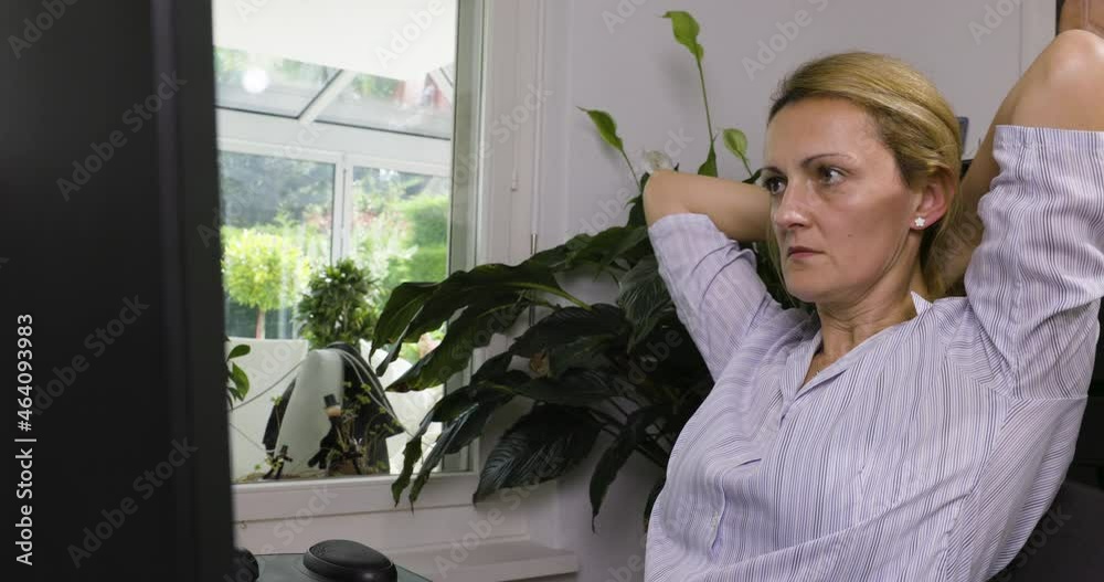 Corona Homeoffice Frau bereitet sich auf Zoom-Meeting mit Vorgesetzten vor. Sie streckt sich, fährt durchs Haar und macht sich bereit.