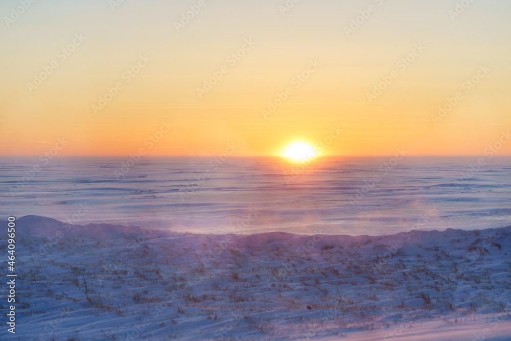 The sun setting over a an expanse of ice and mist.