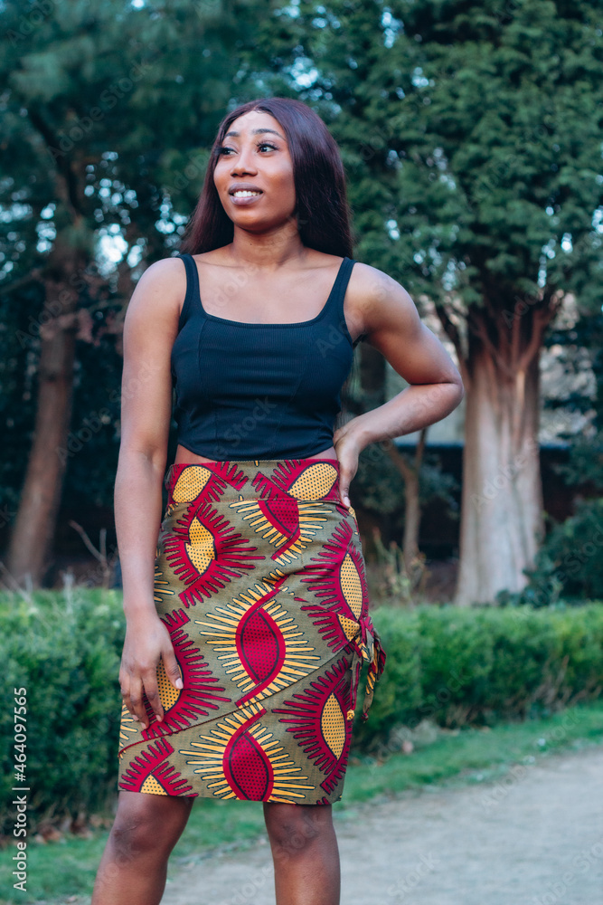 Beautiful African black woman walking in park. Beautiful young woman with brown skin. Strong black woman with wearing print skirt and turban. Beautiful African black woman walking in park. Beautiful young woman with brown skin. Strong black woman with wearing print skirt and turban.