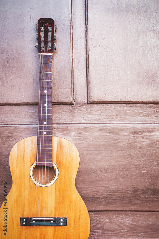 Naklejka premium Yellow traditional soprano ukulele guitar on the steps at the door of a house made of wood. Guitar in front of a wooden house with a door. Music concep.