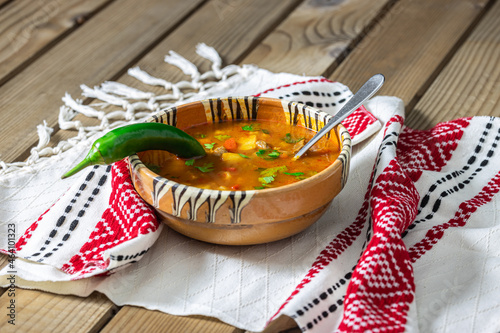 Romanian traditional beef soup served in clay bowl on traditional towel. In romanian is called 