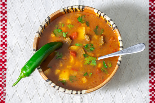 Romanian traditional beef soup served in clay bowl on traditional towel. In romanian is called 