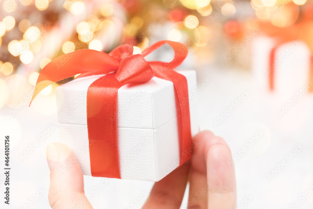 Christmas gift box with red bow holding a man on the background of lights. An offer of marriage on Christmas or New Year with copy space. Christmas gift box with red bow holding a man on the background of lights. An offer of marriage on Christmas or New Year with copy space.