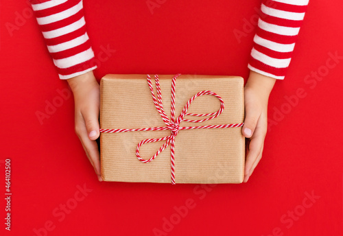 gift box in children's hands on a red background, presenting a gift, christmas background