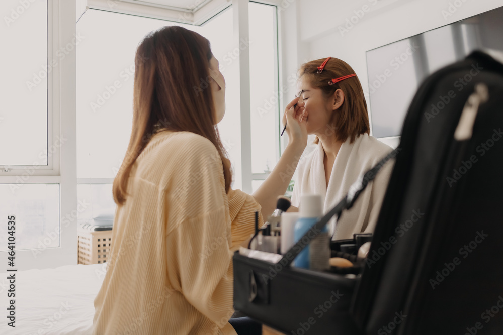 Asian woman makeup artist is at work and wearing makeup on her model. Asian woman makeup artist is at work and wearing makeup on her model.