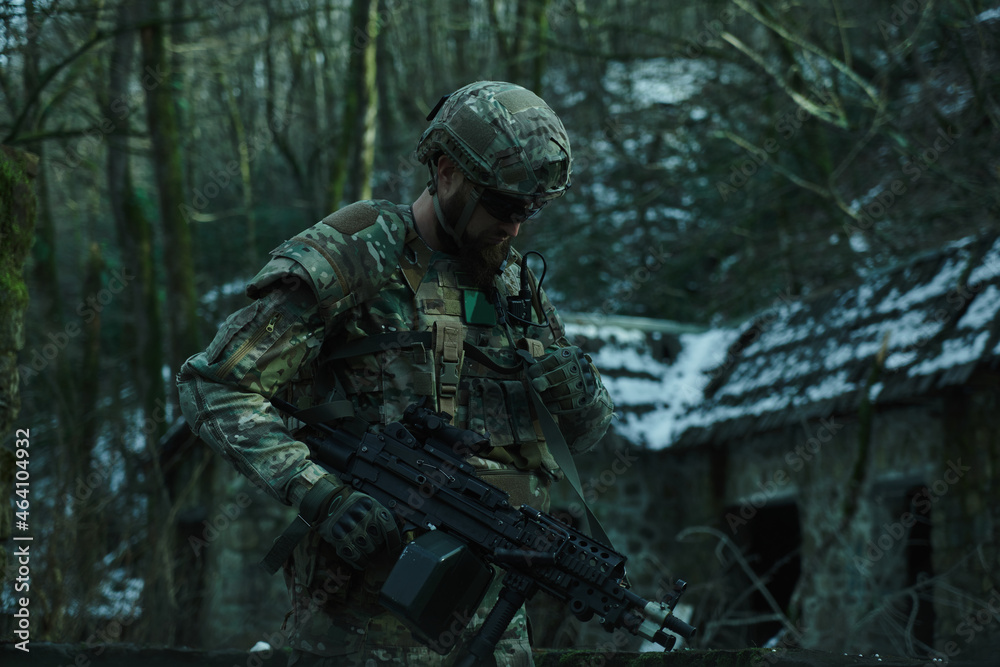 Portrait of airsoft player in professional equipment with machine gun in the forest. Soldier with weapons at war