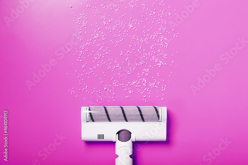 A white vacuum cleaner brush on a pink background.