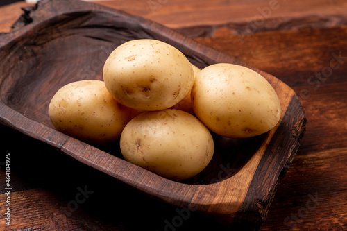 Tubers of large young potatoes on a wooden background. photo