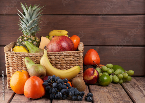 Mix of fresh juicy colorful exotic tropical fruits in basket on wooden background