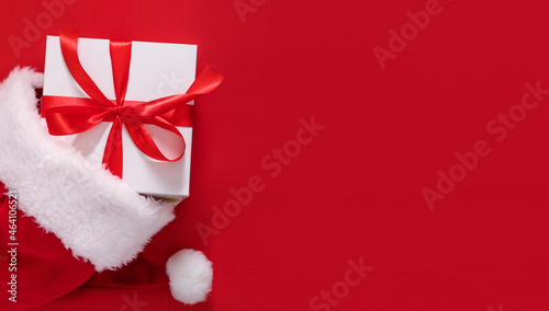 gift box in a hat santa claus on a red background top view with place for text © Екатерина Клищевник