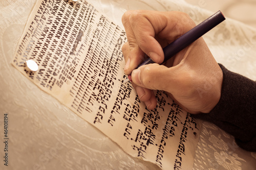A writer's hand, practices decorating letters from a Torah scroll written on parchment in Hebrew, (for the editor - the Hebrew letters are random - without meaning)