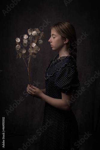 Classic studio portrait of woman in dress holding dried lunaria honesty money flower photo