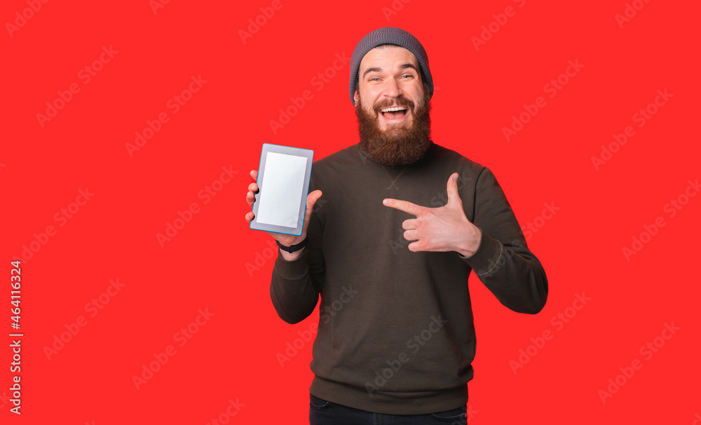 Smiling bearded man is pointing at the tablet he is holding. Smiling bearded man is pointing at the tablet he is holding.