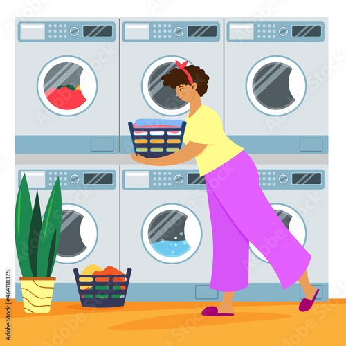 Happy woman in self-service laundromat with clothes