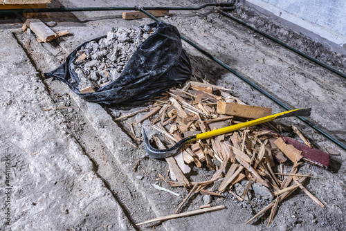 Crowbar on construction waste debris in black plastic bag and on old concrete floor  demolished room  close up view