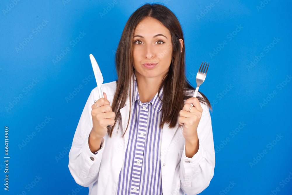 hungry young european doctor girl wearing white medical gown on white background holding in hand fork knife want tasty yummy pizza pie hungry young european doctor girl wearing white medical gown on white background holding in hand fork knife want tasty yummy pizza pie