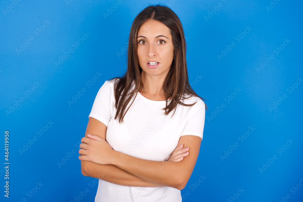 Shocked embarrassed young european girl wearing white t-shirt on white background keeps mouth widely opened. Hears unbelievable novelty stares in stupor Shocked embarrassed young european girl wearing white t-shirt on white background keeps mouth widely opened. Hears unbelievable novelty stares in stupor