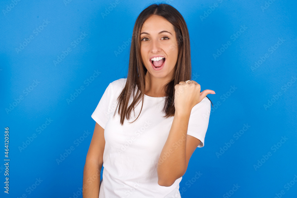 Impressed young european girl wearing white t-shirt on white background point back empty space Impressed young european girl wearing white t-shirt on white background point back empty space