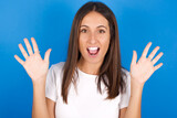 Delighted positive young european girl wearing white t-shirt on white background opens mouth  and arms palms up after having great result