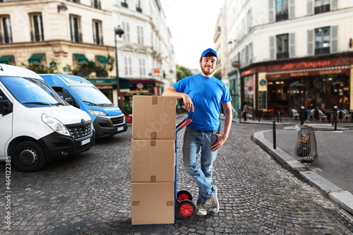 Man with blue uniform in front of the shops for delivery and pickup of the goods